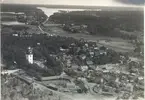 Flygfoto över Kristdala. Samhället med kyrkan, bostadshus och grusvägen.