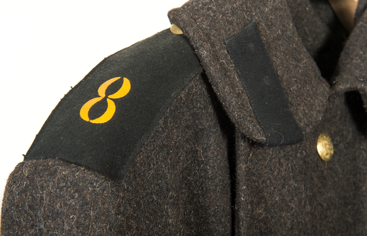 Kappa av brun vadmal, lång, fodrad. Krage, axelklaffar märkt "8” i gul färg. Slejf i ryggen. 9 st mässingsknappar, dubbelknäppt.
Tillhör ryska matrosuniformen. Se O 04826.