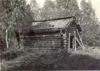 En bod med liggtimmer, korsknutar och torvtak vid Avesjön, mellan Fogelfors och Grönskåra.