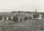 Arbetarebostäder vid norra ändan av bruksgatan.
Längst upp syns det gamla samt ett nytt magasin.
Bakom det senare skymtar den fram till landsväggen flyttade huvudbyggningen.