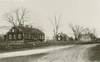 Röda skolan 1923. Harbyvägen gick på den tiden genom kyrkogården och alldeles förbi skolan. Vägen flyttades till sitt nuvarande läge i samband med en utvidgning av kyrkogården i slutet på 1930-talet.