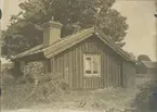 Arbetarstuga av korsknutat timmer. Tak av torv samt tegel.