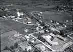 Flygfoto över Skogsby. Kyrka, skola och hus samt vägar.