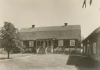 En gård med bostadshus med mansardtak och en ekonomibyggnad.