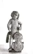 Skulpturen är en putto. En allegorisk liten amorin som ofta ingick som staffage i altaruppsättningar eller (ännu vanligare) på orgelfronter. De hade i sina händer olika ikonografiska föremål som tydliggjorde sammanhangen.