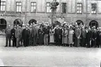 Grupporträtt av okända människor framför Eoska huset vid Larmtorget.