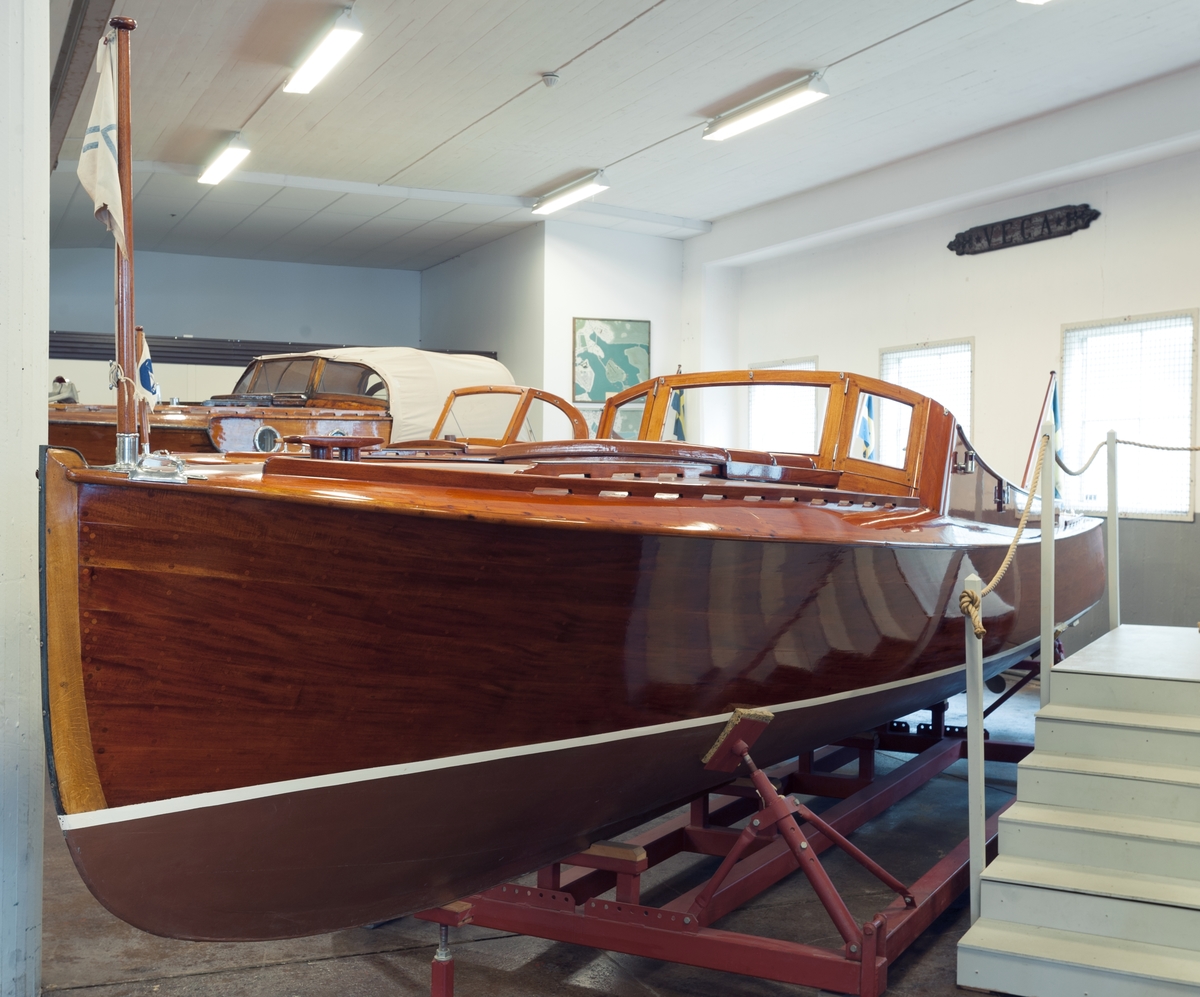 Kravellbyggd mahognymotorbåt, s.k. "Forslundsracer". Byggd på Sjöexpress varv på Lidingö 1928–1929.
Tillbehör till båten: 2 korgstolar, 7 dynor, 2 durkmattor, 1 kapell med bågar, 1 svensk flagga, 1 standert, 6 däcksmattor, 1 par åror i mahogny, 1  båtshake i  mahogny, 1 gösstake i mahogny, 1 lanternstång (akterlig) i mahogny med lanterna, 1 bensinmätsticka och 1 rorkult i mahogny.