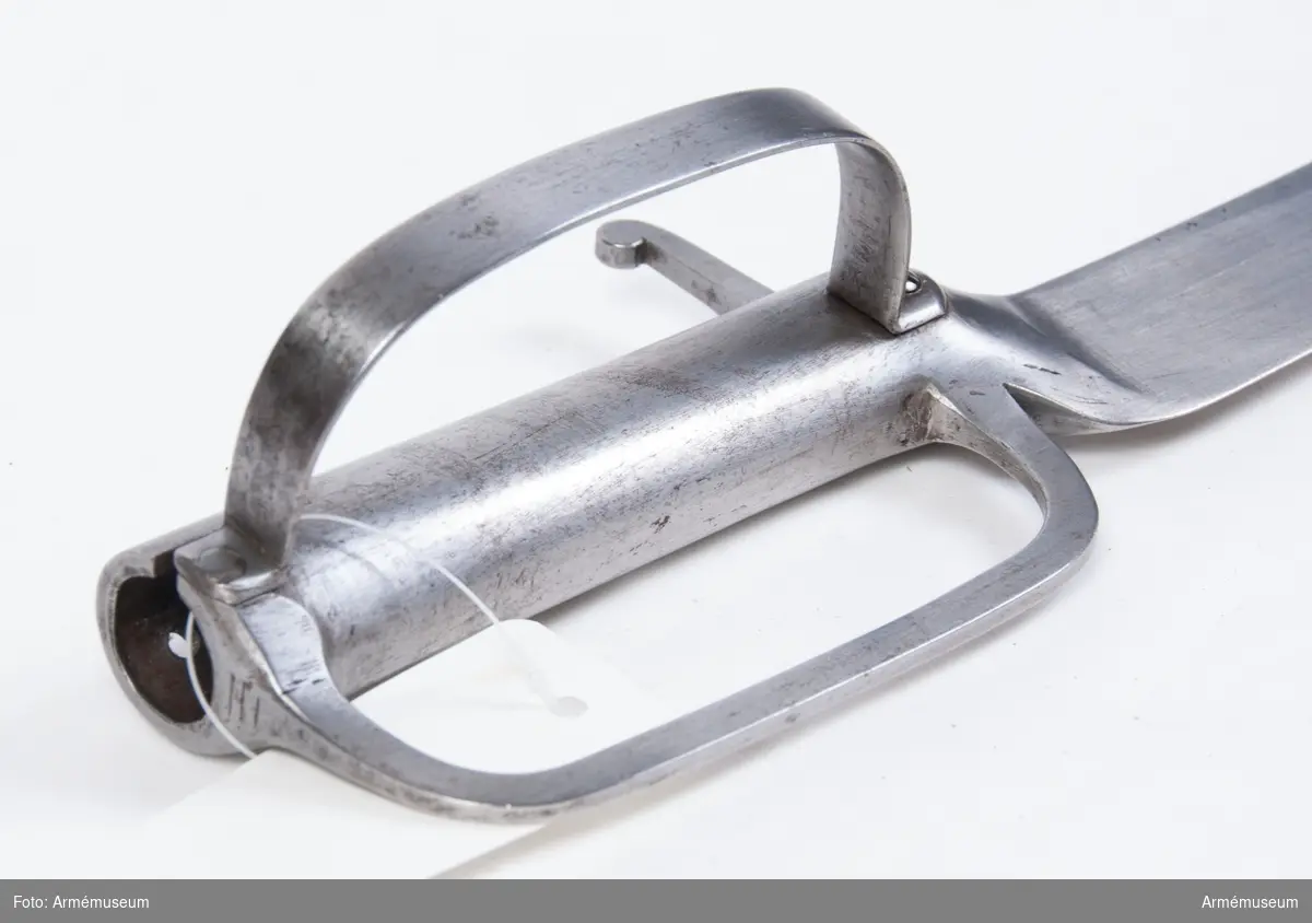 Klingans största bredd är 50 mm (250 mm ovanför udden).
Vapnet är likt AM 36648 (tidnr. 5137), utom att klingan är något kortare, samt att fästet på yttersidan har en bugel som går från korset tiil kavelns övre ände. På det förstnämda stället, fasthålles den av skruv, på den sistnämnda av en nit.