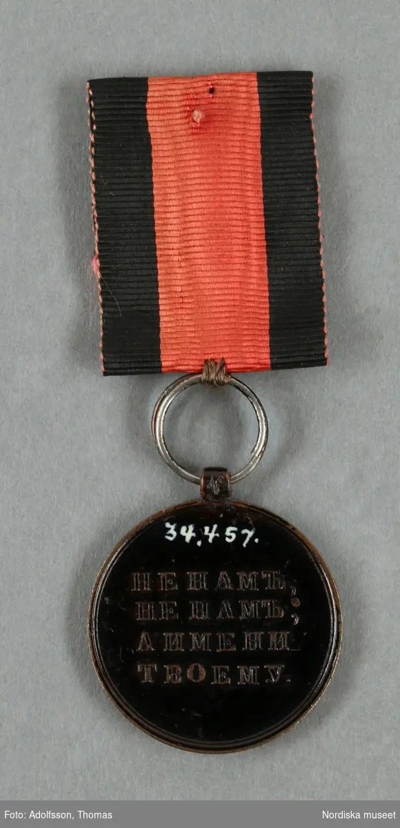 Huvudliggaren:
"Medalj. Se 34.443 [= 34.443-34.485 samlade af friherre Bennet.] 
I tenn, svartmålad. Å ena sidan: Det allseende ögat med strålar; nederst 1812 [och 4 "bokstäver]. Å andra sidan 'HE HAMb, HE MAb ANMEHN TBOEMY [liknande, trol. kyrilliska bokstäver, se huvudliggaren för korrekt avskrift], i fyra rader. Diam. 8 1/2 lin. I rödt, vattradt sidenband med svarta kanter.
Ink. ss. 34.424 [=ink. ss. 34.422  jämte 34.425-34.485]. [34.422=Ink. af byggmästare E. A. Boman i Stockholm 8/1 1883]"