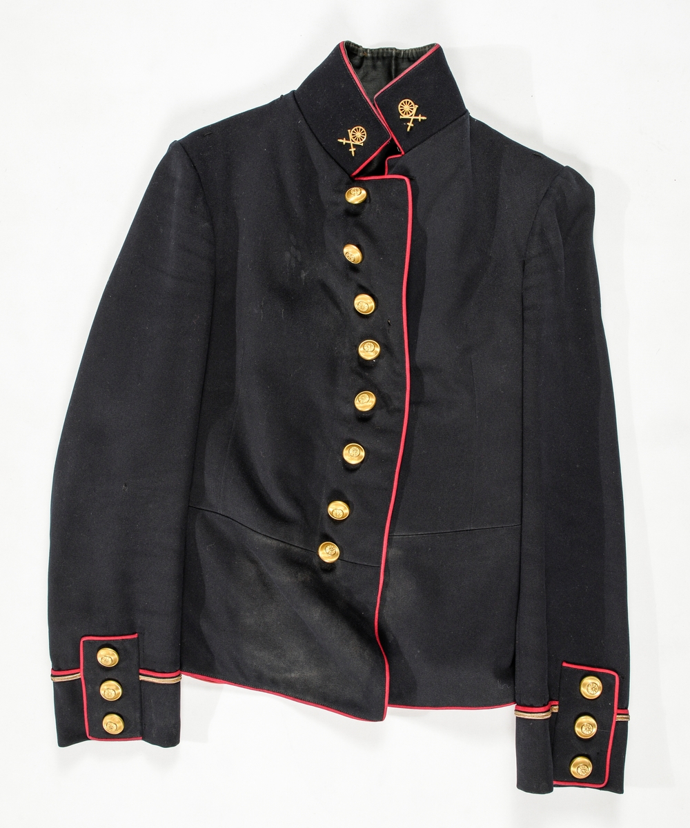 Uniform, løyntnantsuniform, i svart klede med kantar i raudt klede. Registreringa inneheld A. Trøye, B Bukse, C Band med duskar. Trøya har ståkrage, enkel knapping med  åtte knappehol og åtte blanke knappar. Knappane har motiv av eit "hjul". Todelt erme med oppbrett, raude kantingar, gullsnor og tre knappar. Fóra med raudt glatt bomullsfor. Framstykket er vattert.
Buksa (B) har breie raude kantingar i sidene. Gylf med knapping. Linning med splitt og spensel midt bak. Ei lomme på kvar side.
Band med duskar (C) Kypertvevd raudt med duskar i endane. To metallspenner. (C ligg i eske i reol A, seksjon 2, fag III, hylle 2b)