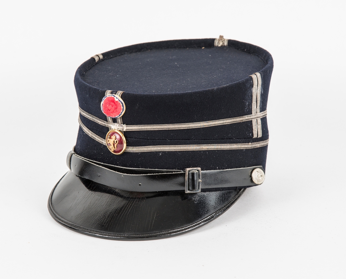Uniform, løyntnantsuniform, i svart klede med kantar i blått klede. Registreringa inneheld A. Trøye, B Bukse, C Lue, D og E Pålettar. Sjå nærare fyldig registrering på arkivkort frå 1969.