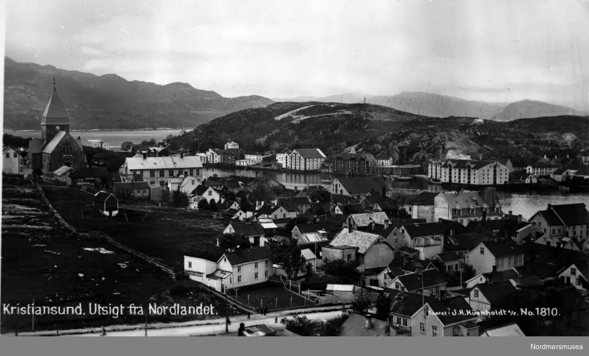 "Kristiansund. Utsigt fra Nordlandet." Foto fra Nordlandet i Kristiansund, med Nordlandet kirke til venstre. I bakgrunnen ser vi fra Innlandet. Datering er ca. 1915-1925. Postkortet er utgitt av J. H. Küemholdt a/s. som nr. 1810. Fra Nordmøre museums fotosamlinger.