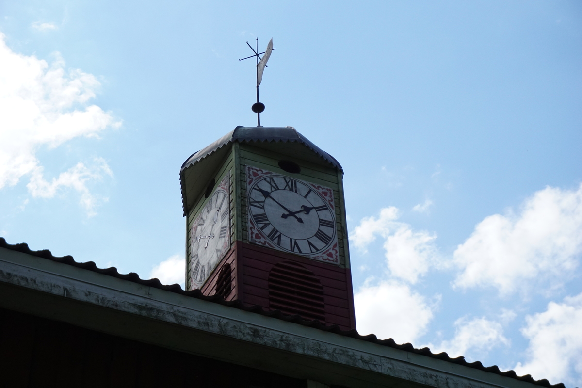 Hovinsholm, Nes, Ringsaker. 
Lukket klokketårn med illuderte urskiver på fire sider. Klokketårnet har et lavt hjelmformet kobbertak. Tårnet er plassert på en rød sokkel.