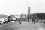 Människor på Östra Torget i Jönköping med Kristine kyrka i bakgrunden. Fotograferat från John Bauers hem.