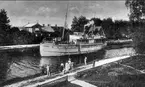 Norra kanalbanken. Båt passerar vid kanalholmen. Gyllenströmska villan syns till höger i bakgrunden, den revs för att lämna plats åt Sandbergs hus. Foto: Alfred Sjöberg, sekelskiftet 1800 - 1900 talet.