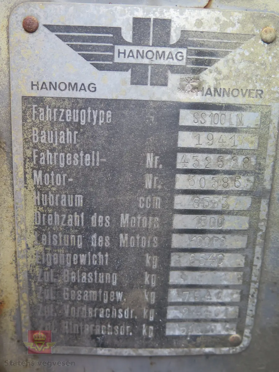 Hanomag SS 100 LN. Ombygd 2 - akslet (4 hjul) maskin med både hydraulisk gravemaskin og lasteskuffe. Gul er hovedfarge (antatt grå originalt). Fra fabrikken ble typen SS 100 LN utstyrt men en vannavkjølt 6-sylindret dieseldrevet motor av typen Hanomag D85S som yter 100 Hk ved 1500 omdreininger. Motorvolum er 8,553 liter. Motornummeret skal være 60386 om motoren er den originale. Maskinens produksjonsnummer er 432528. Girkassen er av typen ZF KB60 med 4 gir framover og ett bakover, pluss overdrive. Topphastighet 65 km/t. Det elektriske anlegget er 24 V. 20 tommers hjul, opprinnelig hadde den tvillinghjul bak. Dører finnes men sitter ikke på.
Har tre merker (stempel) med ørn og hakekors samt plate fra produsenten (på torpedoveggen).
"FROSS-BUSSING" merking i fronten (antatt grill fra en Fross- Bussing).
