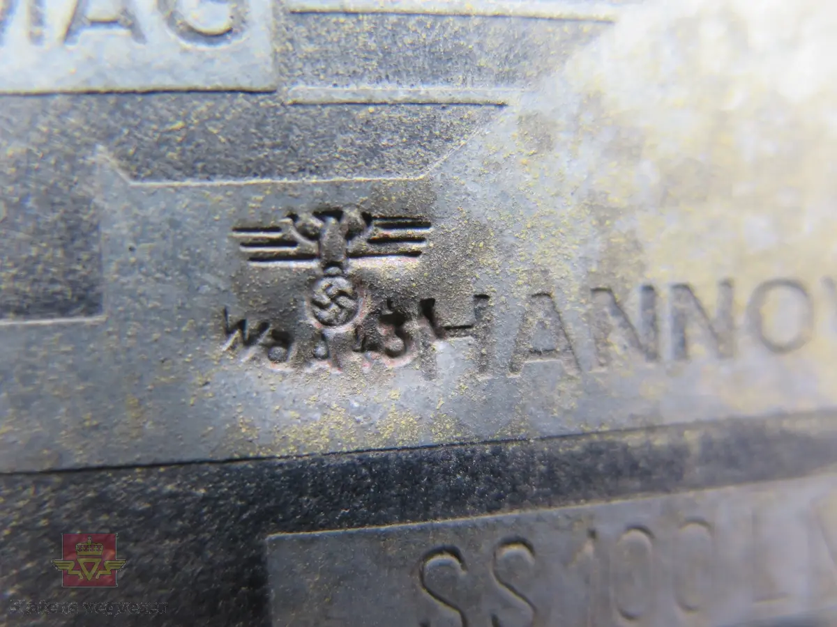 Hanomag SS 100 LN. Ombygd 2 - akslet (4 hjul) maskin med både hydraulisk gravemaskin og lasteskuffe. Gul er hovedfarge (antatt grå originalt). Fra fabrikken ble typen SS 100 LN utstyrt men en vannavkjølt 6-sylindret dieseldrevet motor av typen Hanomag D85S som yter 100 Hk ved 1500 omdreininger. Motorvolum er 8,553 liter. Motornummeret skal være 60386 om motoren er den originale. Maskinens produksjonsnummer er 432528. Girkassen er av typen ZF KB60 med 4 gir framover og ett bakover, pluss overdrive. Topphastighet 65 km/t. Det elektriske anlegget er 24 V. 20 tommers hjul, opprinnelig hadde den tvillinghjul bak. Dører finnes men sitter ikke på.
Har tre merker (stempel) med ørn og hakekors samt plate fra produsenten (på torpedoveggen).
"FROSS-BUSSING" merking i fronten (antatt grill fra en Fross- Bussing).