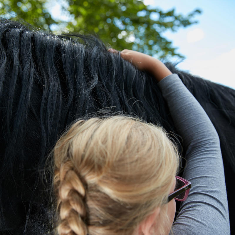 En jente klemmer en svart hest.