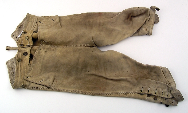 Ett par knäbyxor av ljust skinn.
Sprund vid knät, knäppning med fyra metallknappar.
Knäppning med lucka fram, sex tränsade knapphål.
Sprund mitt bak med tränsade hål för snörning av midjevidd.
Linning, överdel lucka samt del av knäsprund är fodrade med grovt linne.

Gåva till Husaby hembygdsförening av Adolf Svahn som köpt byxorna på auktion efter Petter Larssons barnbarn Erland Johansson, Skattegården, Husaby ( f 1852).

Se bilaga till liggare