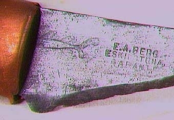 SNICKARE
Kniv med trekantigt blad och holk av koppar vid skaftfogen.
Text i liggaren: "Snick. Rudolf A. Johansson, Skara inrop å aukt. i Skara...Nr 10957-70 tills. 5. kr."
Stämpel å knivbladet i form av en fisk samt texten: E.A. BERG
                                                    ESKILSTUNA
                                                    GARANTI