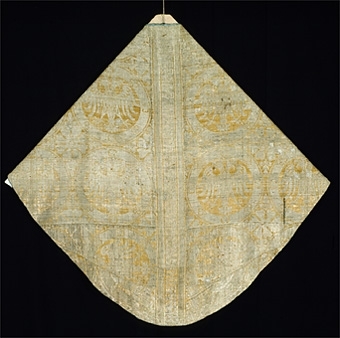 Mässhaken är vävd i s.k. Regensburg-brokad. Dubbelt varpsystem med lin och silke, botteninslag av silke samt mönsterinslag av tarmguld spunnet runt en lintråd. (Taquete alt. samitum)
Tarmguldet är idag bortnött.

Mönstret i form av dubbelörnar inom cirklar har stark anknytning till italiensk-bysantinska mönster. 

Enligt A. Geijer tillverkad i Spanien eller Tyskland.

Litteratur: Medeltida vävnader och broderier i Sverige.
av A. Branting och A. Lindblom. del II, plansch 217, text sid 101 ff.
"Ur Textilkonstens historia", Agnes Geijer. 1972. (sid 162, pl 34 a.)