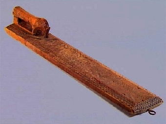 Mangelbräde med skulpterat, hästformat handtag. Karvsnittsdekor i form av rosett, virvelhjul, hjärta. Ristade bladornament, rutmönster mm. Uddsnittsbårder utmed långsidorna bl.a.