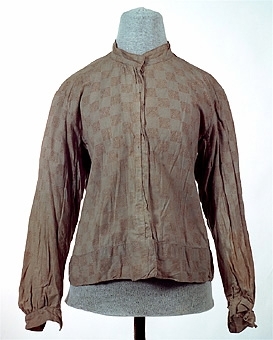 Ljust brunaktigt vit blus sydd av tuskaftsvävt bomulltyg med tryckt mönster i färgerna brunt och ljust blått. Blusens framstycken är fodrade med ett ofärgat bomullstyg medan bakstycket är fodrat med ett röd och vitrutigt tyg. Blusens olika delar är sammanfogade med maskinsöm, kastsöm och förstygn. Knäppning mitt fram av tryck knappar. Ärmarna är avslutade med en manschett som knäpps med en tryckknapp.


Neg.nr: 
Sakord: BLUS
Tillverkningstid: 1920 - 1930
Material: Bomull
Teknik: Vävt tryckt sytt
Mått: L=570
Vikt: