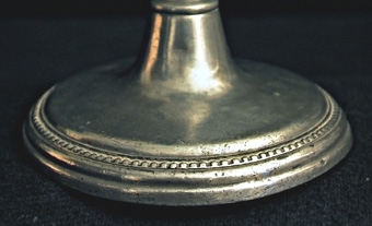 Ljusstake med stor, rund fotplatta. Pärlstav omkring fotplattan och ljusmanschetten.