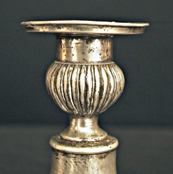 Ljusstake av tenn. Kvadratisk fotplatta med kulor i hörnen. Skaftet balusterformat. Ljushållare med godronnering.