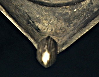 Ljusstake av tenn. Kvadratisk fotplatta med kulor i hörnen. Skaftet balusterformat. Ljushållare med godronnering.
