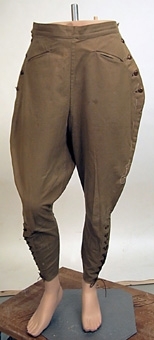 Konfektionssydd ridbyxa av kraftigt bomullstyg vävt i tuskaft. Modellen är sydd med sprund i sidorna vilka knäpps med knappar, två snedställda fickor framtill, linning som knäpps i sidorna  med metallspännen samt sprund nedtill på byxbenen. Dessa sprund hålls samman med en snörning. byxbenen är skurna med mycket vidd upptill och är åtsittande nedtill. Anm. enligt accessionskatalog: "Inköpta 1925 - 1930."