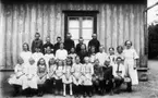 Lärarinnan Naemi Jönssons skolklass i gamla Floby kyrkskola. Främre raden: Karin och Greta Karlsson, Anna Lundin, Stina Karlsson, Ingeborg Johansson, Karin Sofia Gustafsson, Bertil Andersson, Gustav Johansson, Gustav Lindholm. Mellanraden: Ebba Ljunggren, Maj Kindblad, Edit Hedlund, Linnea Eliasson-Hermansson, Stina Hermansson, Märta Berntsson, Greta Johansson, Karin Ottergren, fröken.