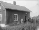 Exteriör. 
Fem herrar framför litet trähus. 
Fotograf: Ellen Kock? Axel Lundbäck m.fl. 
Gullspångssamlingen.
Bilder från Gullspång med omnejd.