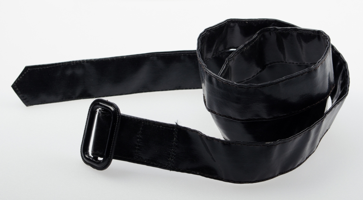 Barnejakke i plastbelagt bomull med knappelukning i front. Fire sorte trykknapper i front. Påsydd krage. Hempe innvendig i nakken. Sydde og smurte sømmer.