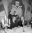 Skara Manskörs 30-årsjubileum, 1951.
Körens ordförande Sam Magnusson mottager vänorten Eidsvolls manskörs gåva. Sittande stadsfullmäktiges ordförande Rudolf Andersson och Västergötlands sångarförbunds ordförande landshövding Richert.