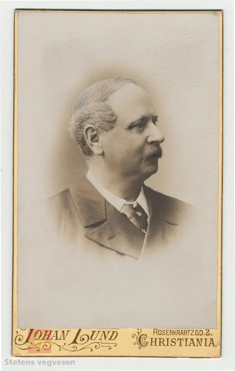 Håndskrevet tekst på framsiden av bildet: "Tilhører Baalsrud (Fra V.D. Krag) 1903." Videre medfølger det håndskrevet tekst til bildet: Sitat: "Krag og Vegdirektør Bergh prøver rullekjerre, bygget for billige veger." Bildet viser presentasjon av rullekjerren, som skulle bli det nye kjøretøyet for høyfjellsvegene, men ikke ble noen suksess. 
Dette bilde er vistnok tatt i et gårdsrom i Haugesund. Til venstre sitter daværende vegdirektør Bergh og til høyre seinere vegdirektør Krag. Usikkert når bilde er tatt, Christian Wilhelm Berg døde i 1873 så bildet er tatt før den tid, og det er trolig det eneste fotografiet vi kjenner hvor Christian W. Bergh er avbildet. Følg pilen til høyre for flere bilder. I alt 7 bilder.
Ref. til "Meddelelser fra Veidirektøren," nr. 2-1945, side 24, der bildet er illustrert i en artikkel om "Rullekjerren," av H.W. Paus. 
Ref. til "Årbok for Norsk vegmuseum 2016," en artikkel om Vegdirektør Krag - "Heller en tarvelig vei enn ingen vei," ved Ane Cecilie Røed. I boka er samme bildet side 101 som i "Meddelelser fra Veidirektøren," nr. 2-1945)
Utsnitt fra Ane Cecilie Røed sin artikkel:
Rullekjerren
"Som vegmann var Krag opptatt av nye ideer og initiativ for å bedre framkommeligheten. Han var også interessert i ulike framkomstmidler noe denne historien illustrerer. Befolkningen i Skjåk hadde lenge ønsket seg en kjøreveg over fjellet til Vestlandet, og da gjerne til Tafjord. Krag på sin side ville at vegen, en simpel kjøreveg, skulle gå over Grotli og slik ble det. Da vegen var nesten ferdig, viste det seg at man ikke kunne kjøre på den med vogn. Til det var vegdekket for løst og vegen for smal. En rullekjerre, som enten var en kjerre med to brede hjulfelger, eller en trommel eller rulle, ble lansert og ble begeistret støttet av Krag.  Det sies om rullekjerren at den allerede i begynnelsen hadde det med å løpe løpsk og rulle sine passasjerer omkull. Da vegdirektøren og ordføreren skulle prøvekjøre den nye farkosten, endte de i grøften, med bygdefolket som nysgjerrige tilskuere. Kort tid etter var rullekjerren en saga blott, og på den nye vegen kjørte man med bredfelgede kjerrer (Schulerud 1974 s 301-302). Historien om rullekjerren bekrefter på lik linje med andre episoder i denne artikkelen, Krags brede interessefelt og engasjement. "
Se artiklene i Nedlastinger og Referanser lenger ned på siden.
Et eget Vegdirektorat kom først i 1864, og Christian Wilhelm Berg var den første vegdirektør i perioden 1864 - 1873.
Etterfulgt av  Hans Hagerup Krag i 1874 - 1903,  Johan Christian Skougaard 1903 - 1918 og Andreas Baalsrud i perioden 1919 - 1945. 
Bilde 2) Vegdirektør Christian Wilhelm Bergh.  Bilde 3) Vegdirektør Hans Hagerup Krag. Bilde  4) Vegdirektør Johan Christian Skougaard. Bilde 5) Vegdirektør Andreas Baalsrud. Se vedlegg i Nedlastinger for mer informasjon.
Bilde 6) Rullekjerren.  I følge «Meddelelser fra Veidirektøren Nr. 2-1945, side 24, er dette bilde av rullekjerren tegnet av overingeniør Fenger Krog.
Bilde 7) Informasjon om rullekjerren ved Norsk vegmuseum sin første utstilling 1992.