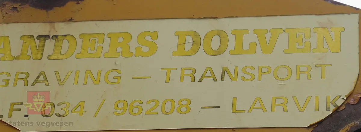 Gravemaskin, hjulgående. 2 jernhjul foran og 2 gummihjul bak. Maskinen er oransje med svart sete. Motoren er en 4-sylindret dieseldrevet type fra Perkins. Gravemaskinen var ikke selvgående, men forflyttet seg med gravearmen under arbeid. Ved transport mellom arbeidsstedene hektet en skuffen i lasteplanet og løftet opp "forhjulene" slik at den ble transportert som en henger.