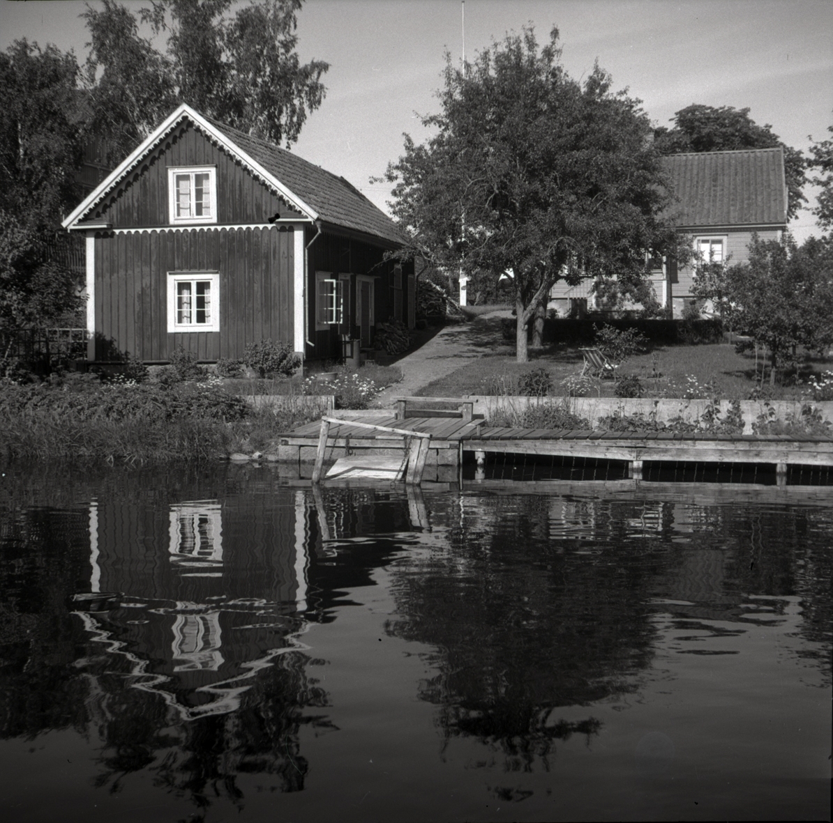 En bod och bostadshus med vatten och brygga i Figeholm.