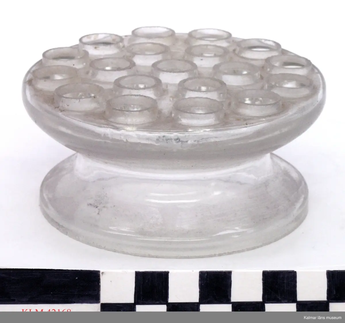 KLM 42168 Blomhållare, glas. Ofärgat glas, rund platta helt täckt av runda hål, på fot.