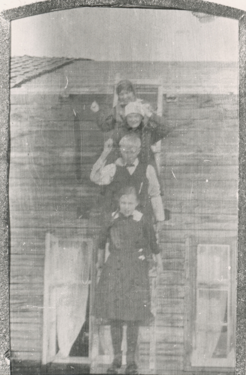 Fire barn på en stige foran et hus.