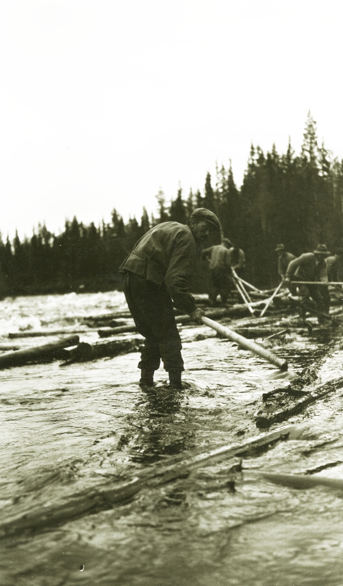 Menn stående uti elva - i gang med fløtinga. Mann nærmest kamera: Olaf O. Flermoen (1/1 1880, Akerhaug, til USA). Ved Kvarnstrandfossen ved Stor-Grøna.