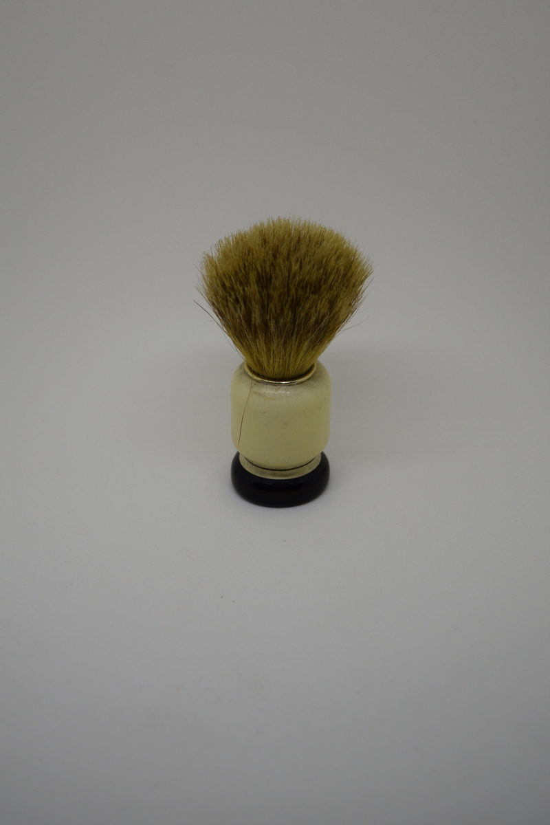 Barberkost med søyleformet skaft og en langsgående hulkil. Dreiet skaft/sokkel m/et stort hull. Bust tappet ned i dette. Holdt på plass av en lettmetallring. Malt og lakket.
