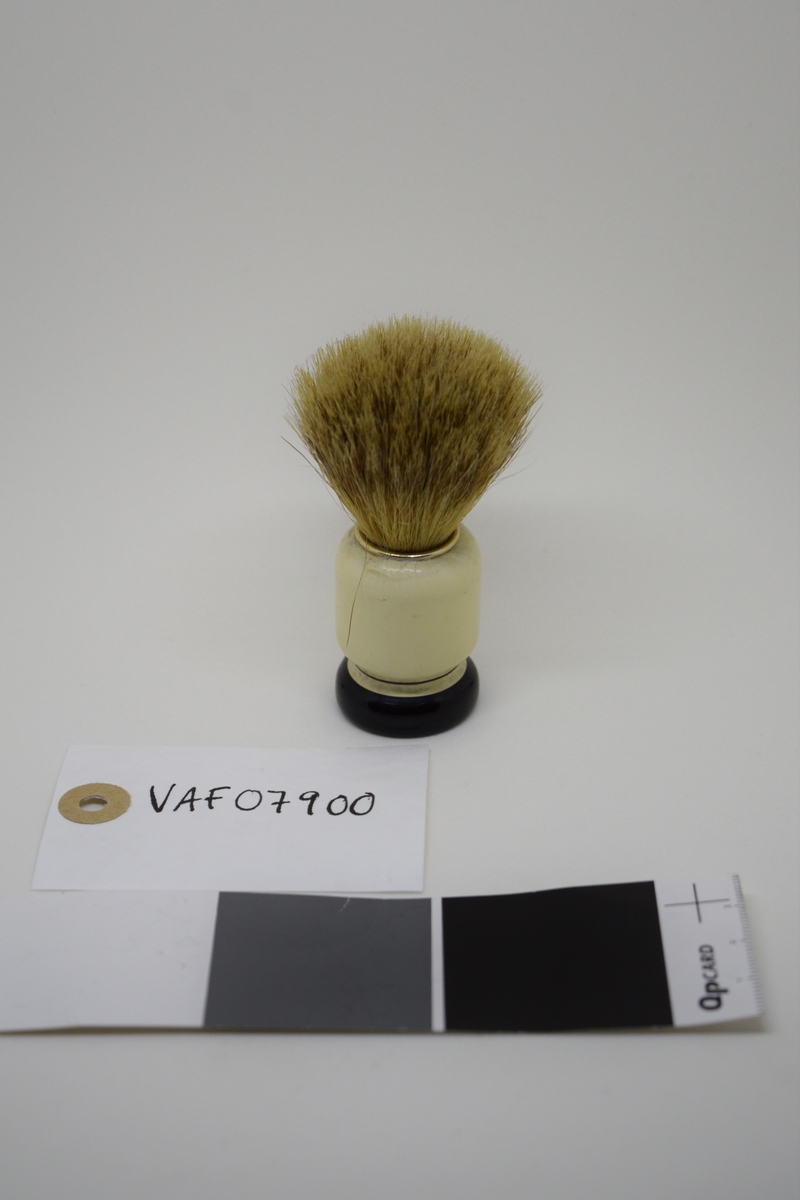 Barberkost med søyleformet skaft og en langsgående hulkil. Dreiet skaft/sokkel m/et stort hull. Bust tappet ned i dette. Holdt på plass av en lettmetallring. Malt og lakket.