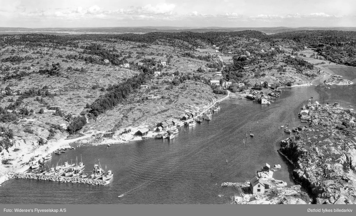 Utgårdskilen med molo, fiskebåter  og sjøbuer, Hvaler, flyfoto fra juli 1964. Sørlendingen i forgrunnen til høyre.