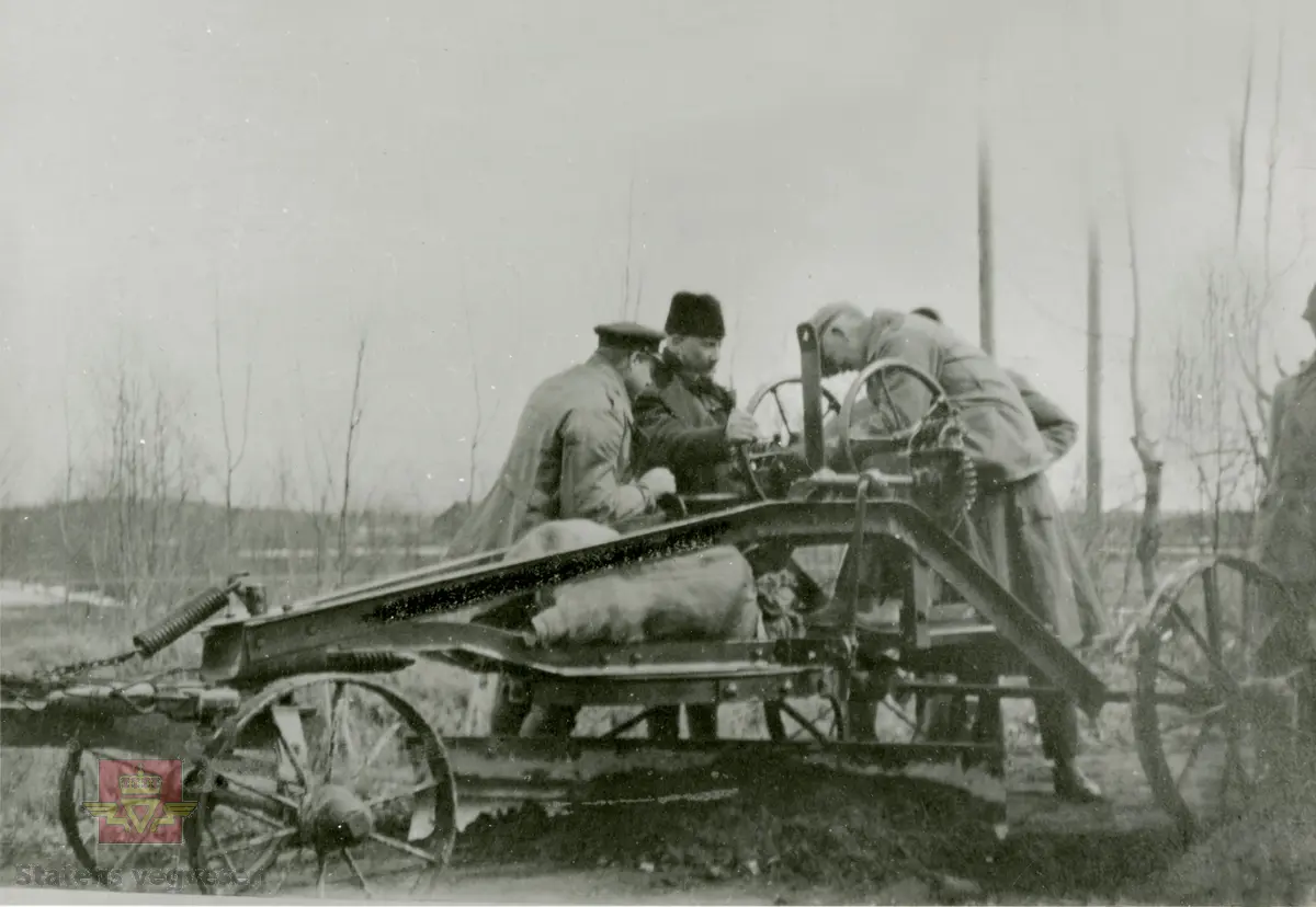 Amerikansk veghøvel "Russel Grader"  i arbeid i Østfold 1924, i følge merking.  Ref. til "Meddelelser fra Veidirektøren", Nr. 47-mai 1924. Artikkel om "Prøve med den amerikanske veihøvel "Russel Grader" samt skrapning av veibanen med "Western" skrape", av overingeniør Thor Olsen. Befaring  med vegdirektoratets og Østfold fylkets ingeniører.  Andre bilder av veghøvelen som er illustrert i artikkelen vises i bilde 2/5 og 3/5. Bilde 4/5: "Skraperne av "Western"-typen forarbeides som nævnt ved fylkets verksted og utstyres nu med en fast arm paa den ene side for styring av hele redskapen foruten den bevægelige for stillingen av bladene , som det vil sees av fig. 5". Bilde 5/5: Vedlikeholdsarbeid med amerikansk vegskrape utføres i Østfold.