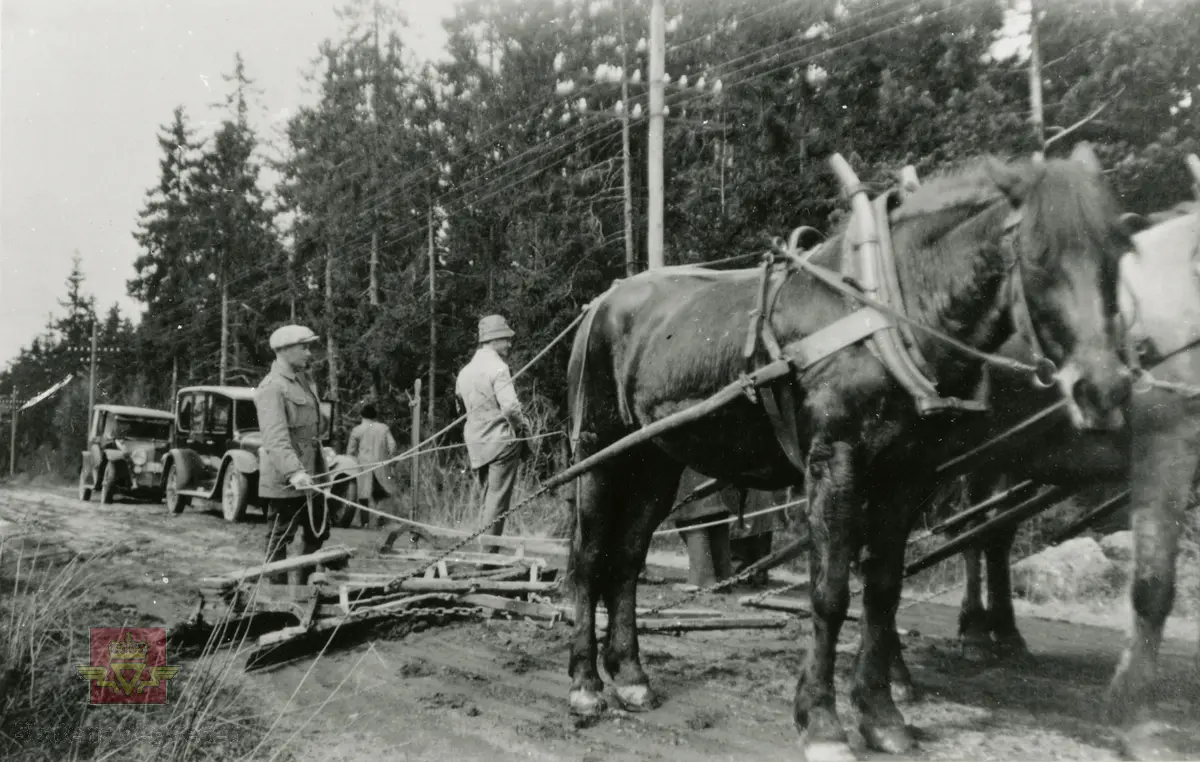 Amerikansk veghøvel "Russel Grader"  i arbeid i Østfold 1924, i følge merking.  Ref. til "Meddelelser fra Veidirektøren", Nr. 47-mai 1924. Artikkel om "Prøve med den amerikanske veihøvel "Russel Grader" samt skrapning av veibanen med "Western" skrape", av overingeniør Thor Olsen. Befaring  med vegdirektoratets og Østfold fylkets ingeniører.  Andre bilder av veghøvelen som er illustrert i artikkelen vises i bilde 2/5 og 3/5. Bilde 4/5: "Skraperne av "Western"-typen forarbeides som nævnt ved fylkets verksted og utstyres nu med en fast arm paa den ene side for styring av hele redskapen foruten den bevægelige for stillingen av bladene , som det vil sees av fig. 5". Bilde 5/5: Vedlikeholdsarbeid med amerikansk vegskrape utføres i Østfold.