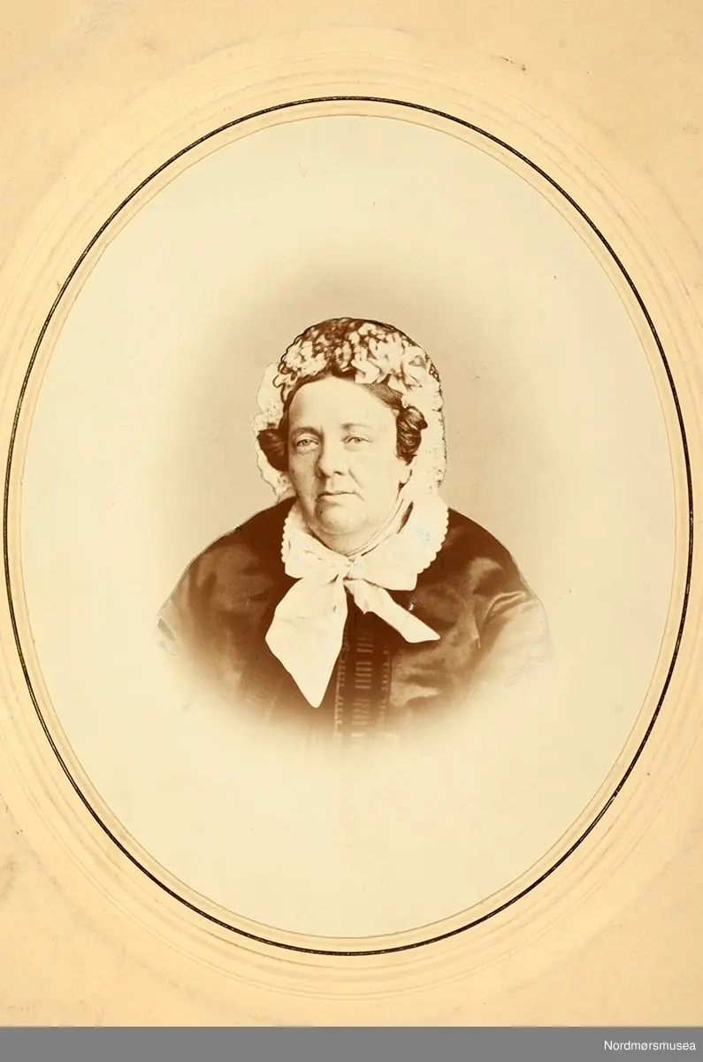 Sannsynligvis  Margrethe Christine Lucie Kaasbøl Knudtzon (Greve) f. 1799 og d. 1882, bestemor til Marie Knudtzon. Oldemor til Marie Knudtzon f. 1879. Portrettet kan være fra 1850-1869, men mest trolig fra siste del av 1860-årene. Kvinnen har silkecape med kniplingekrage. Kysen har kniplinger og bånd knyttet til en sløyfe i halsen. 
(info: Randi Elisabeth Hagen) 

Bilde fra Marie Knudtzon jr (1879-1966) sin fotosamling.  Se bilde nr KMb-2010-011.0001 for mer biografi. Fra Nordmøre museum sin fotosamling,
