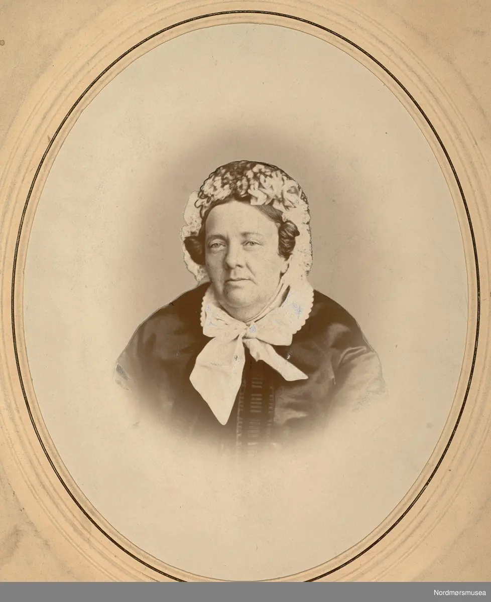 Sannsynligvis  Margrethe Christine Lucie Kaasbøl Knudtzon (Greve) f. 1799 og d. 1882, bestemor til Marie Knudtzon. Oldemor til Marie Knudtzon f. 1879. Portrettet kan være fra 1850-1869, men mest trolig fra siste del av 1860-årene. Kvinnen har silkecape med kniplingekrage. Kysen har kniplinger og bånd knyttet til en sløyfe i halsen. 
(info: Randi Elisabeth Hagen) 

Bilde fra Marie Knudtzon jr (1879-1966) sin fotosamling.  Se bilde nr KMb-2010-011.0001 for mer biografi. Fra Nordmøre museum sin fotosamling,