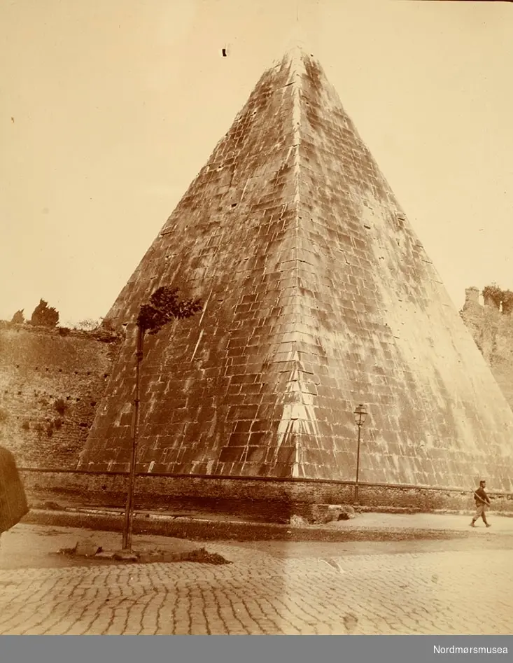 Cestius-pyramiden, La Piramide di Caio Cestio, År 12 f.Kr. Vestsiden av Porta San Paolo, Roma, Lazio, Italia.  
Info: Virginia Bertani 2017. 
Bilde fra Marie Knudtzon (1879-1966) sin fotosamling. Se bilde nr KMb-2010-011.0001 for mer biografi. Fra Nordmøre museum sin fotosamling.