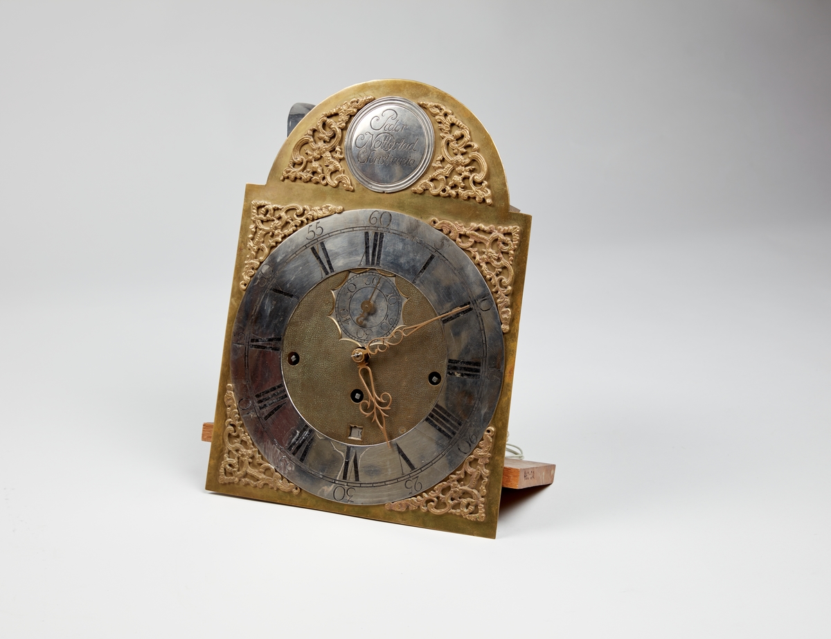 Gulvur i antatt sekundær kasse. Buet toppstykke med brutt gavl og vinduer til urverket på sidene. Rektangulær hoveddel med svungen sokkel nederst. Toppstykket dekorert med utskåret gitterverk øverst samt tre kuler på gesimsen og søyler på hver side av lysåpningen. Hoveddelen av kassen med pendeldøren er udekorert, sokkelen dekorert med utskåret gitterverk samt blader (akantus) på sidene og musling på midten nederst. Hele kassen malt ensfarget rød, kulene på gesimsen er sorte.

Urverk av messing forsynt med spillverk med elleve bjeller (visstnok til to melodier) samt én timeslagbjelle. Støpt dekor i tallskivens hjørner, hovedsakelig bladverk og c-formede ornamenter i et intrikat mønster. Midtfeltet er finhamret uten annen ornamentikk. Forsølvet timering og stjerneformet sekundring samt navneplate med signatur øverst og datoring som vises over sekstallet nederst.